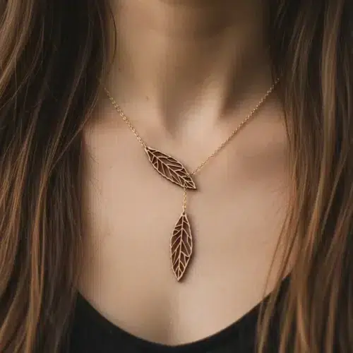 Collier Ekinox en bois avec pendentifs feuilles en bois suisse sur chaîne dorée, porté sur la poitrine d'une femme avec cheveux bruns