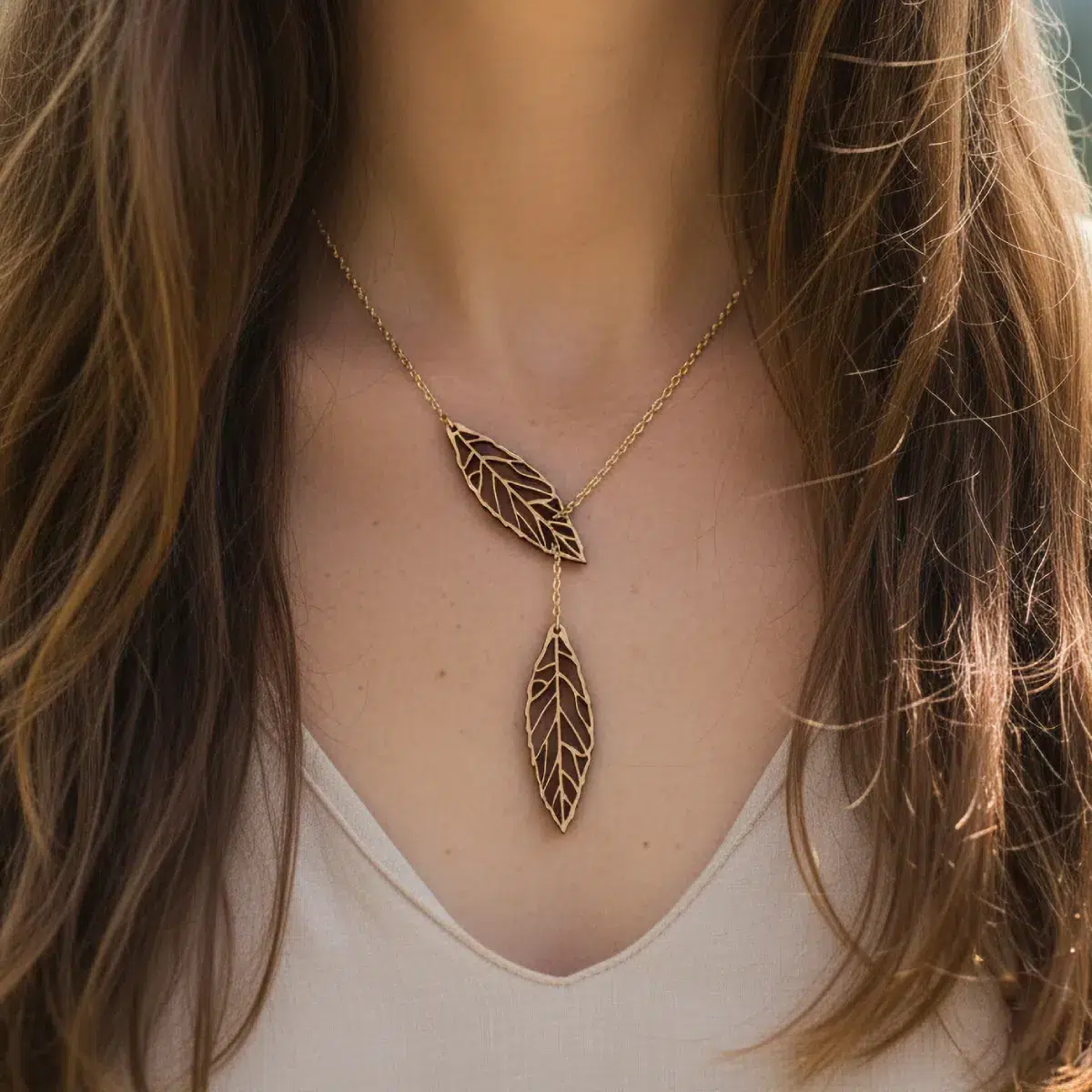 Collier Ekinox en bois avec deux pendentifs feuilles en bois suisse sur chaîne dorée, porté sur la poitrine d'une femme avec cheveux châtain clair